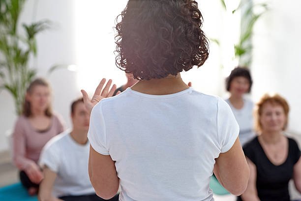 Rear view of female instructor guiding student during yoga class